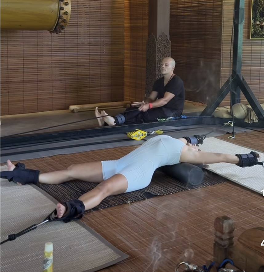 An assisted stretch session on a mat, therapist working through a hamstring