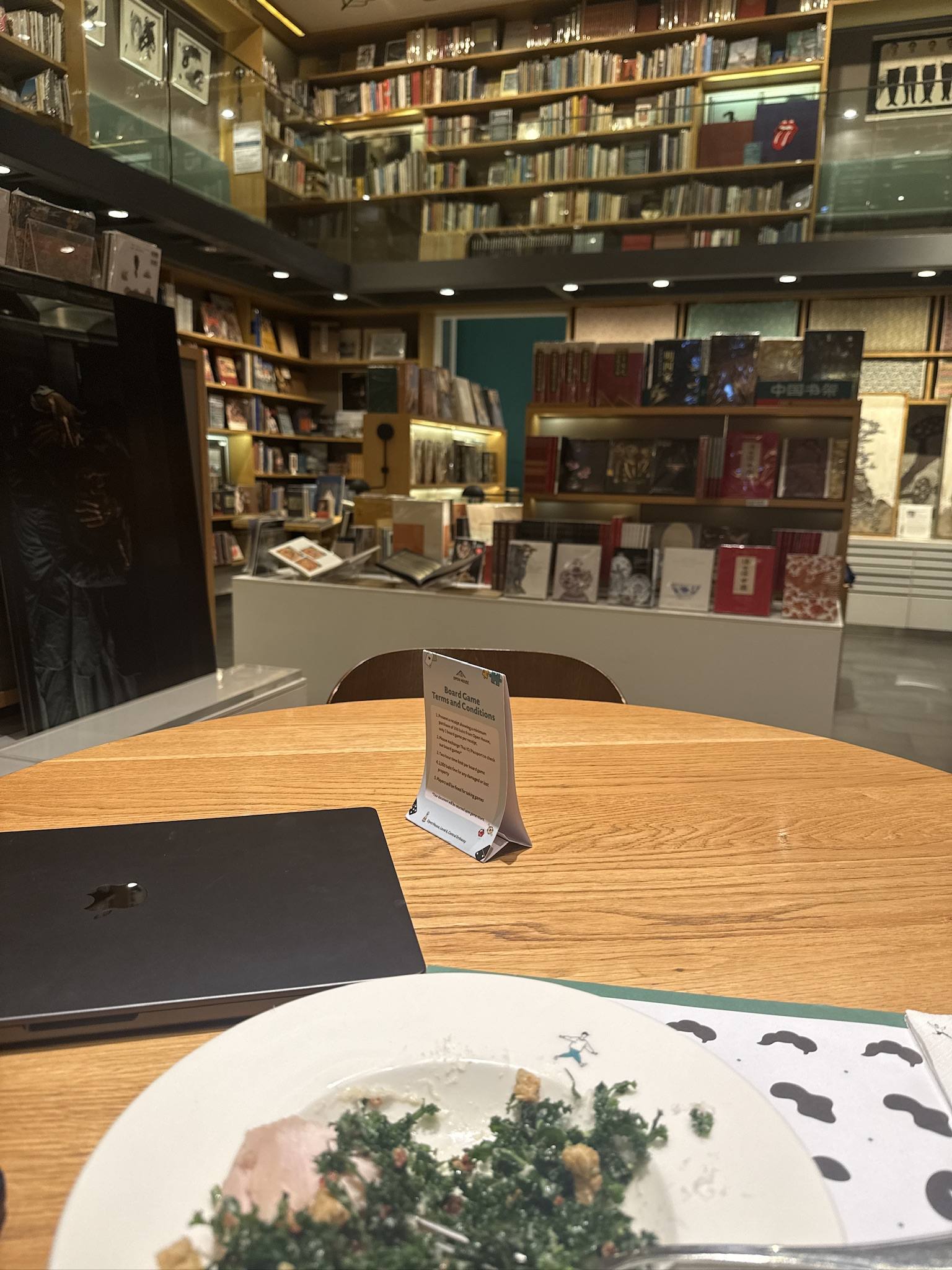 A laptop and a plate at a round table inside a bookshop