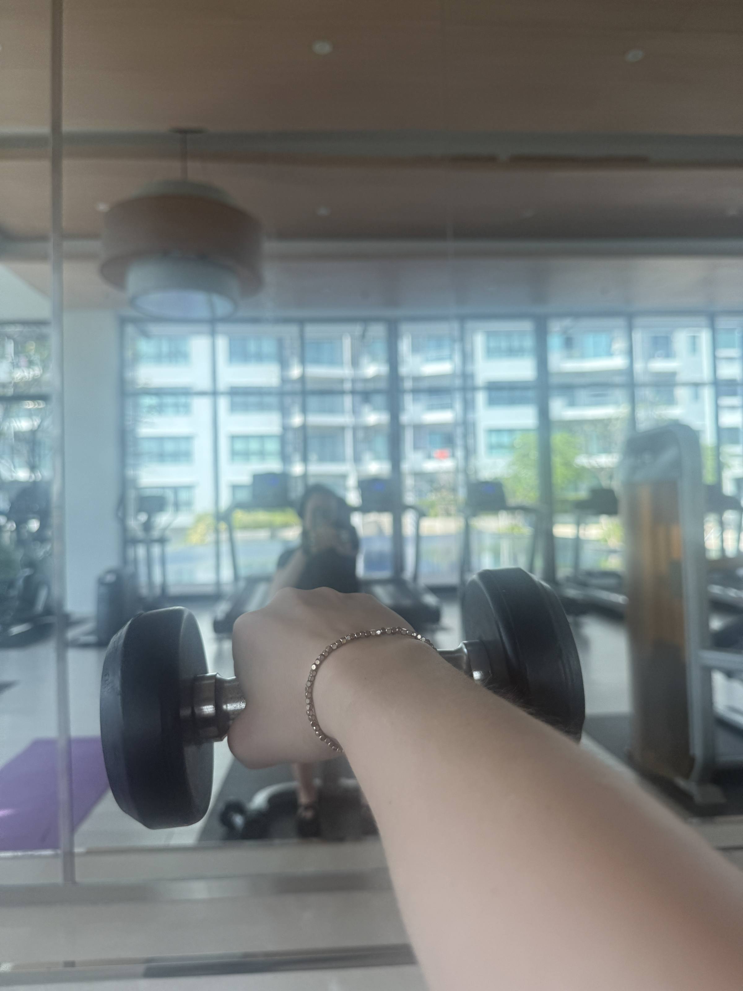 Holding a dumbbell in a gym with floor-to-ceiling windows
