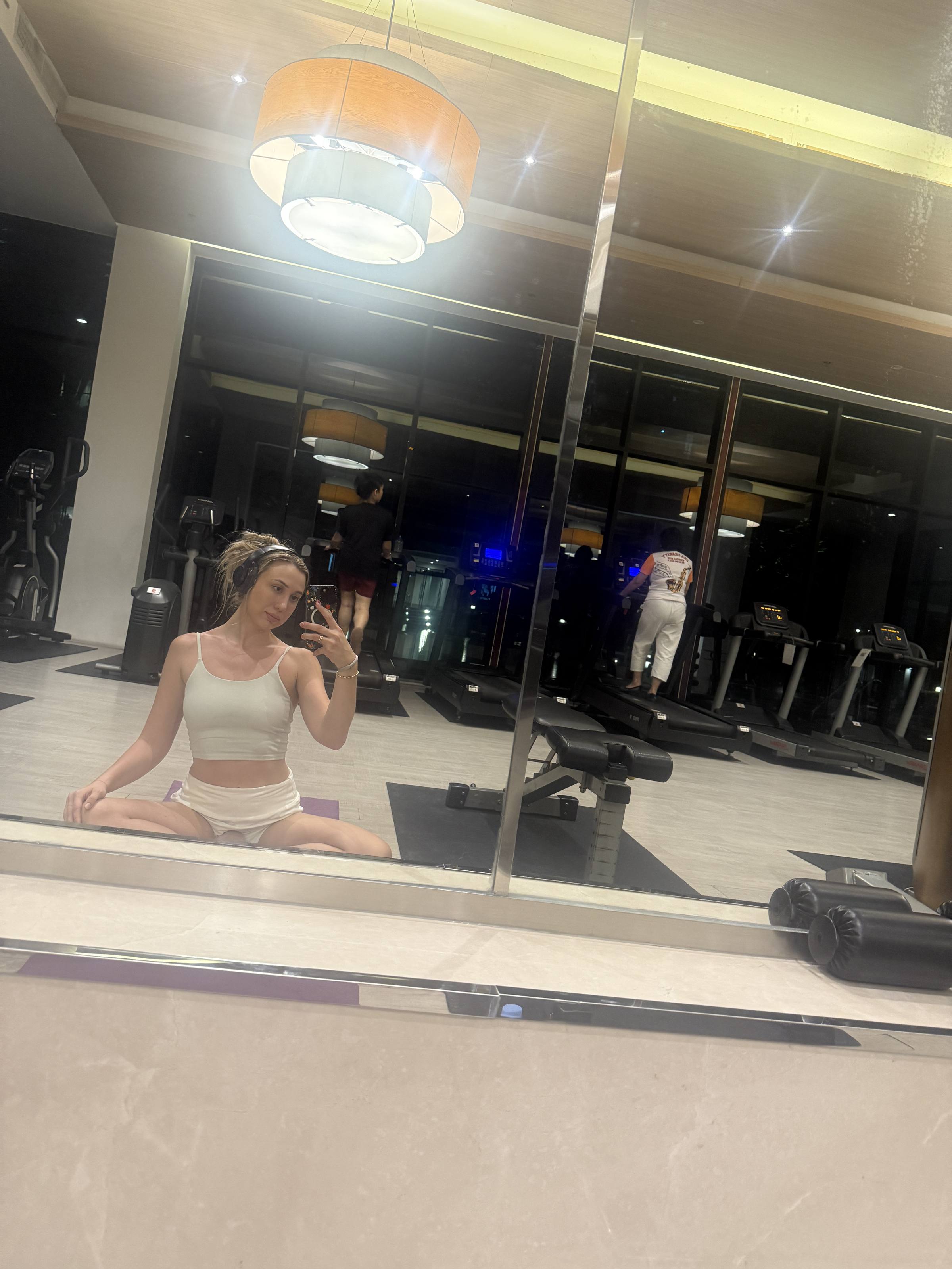Stretching on the mat in a hotel gym, mirrors and equipment behind