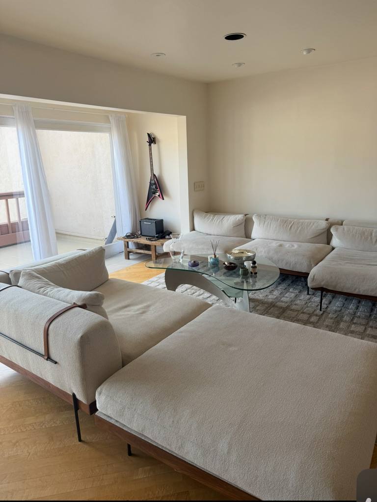 A long cream sofa and glass coffee table in a bright living room