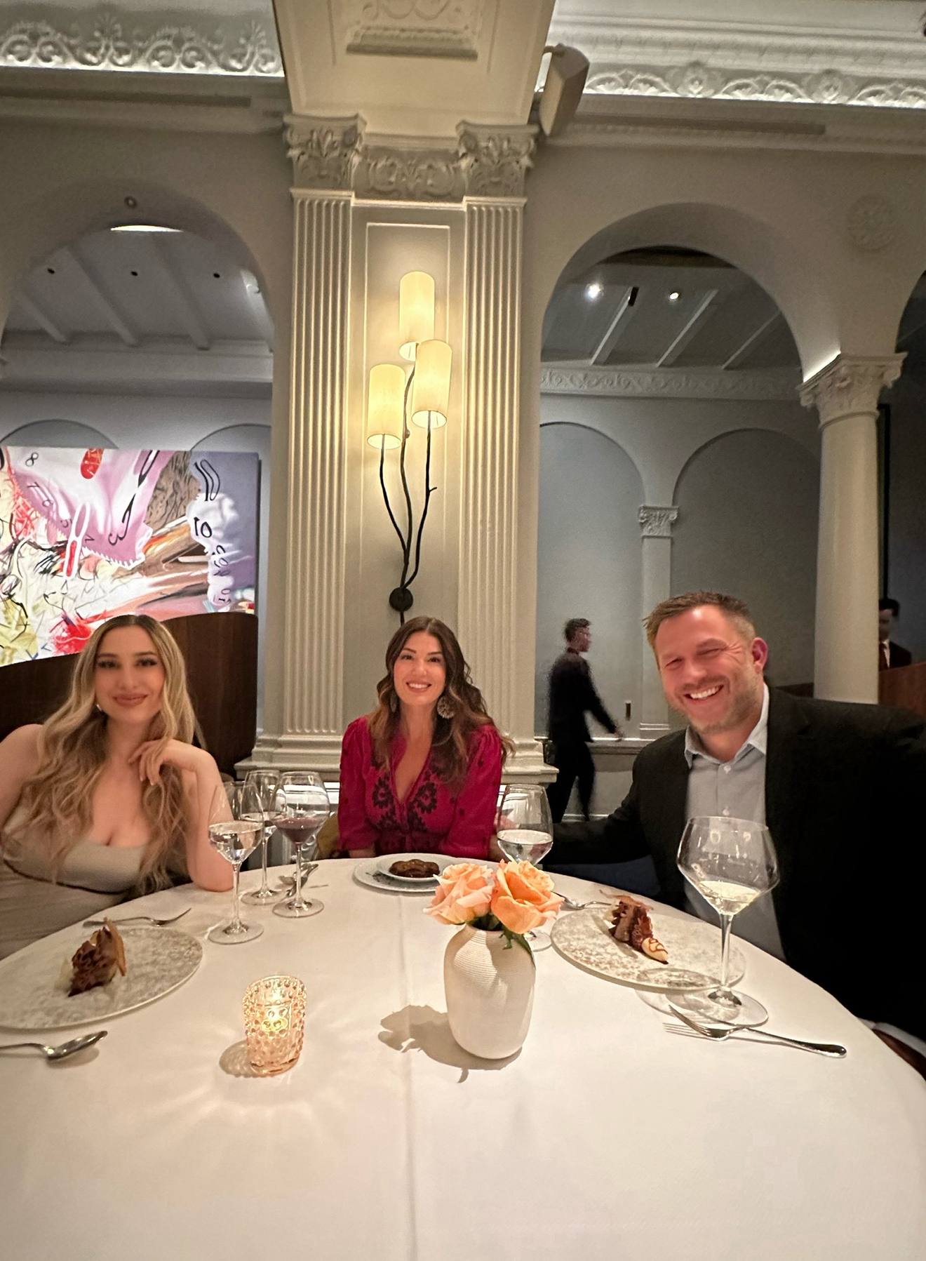 Dinner in a grand dining room, white tablecloths and columns