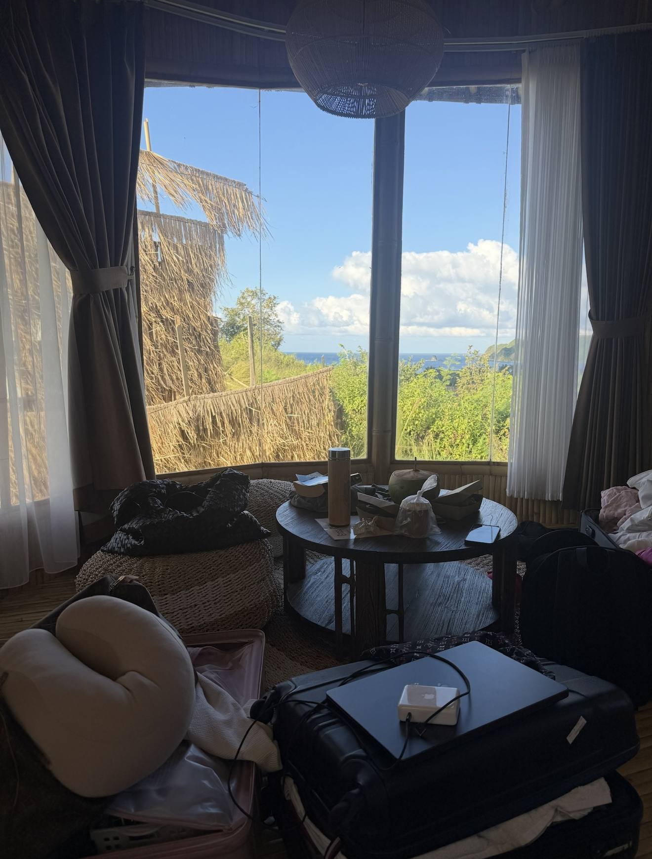 An open suitcase and bags in a room facing the ocean