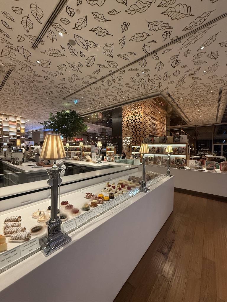 A long patisserie counter under a leaf-patterned ceiling