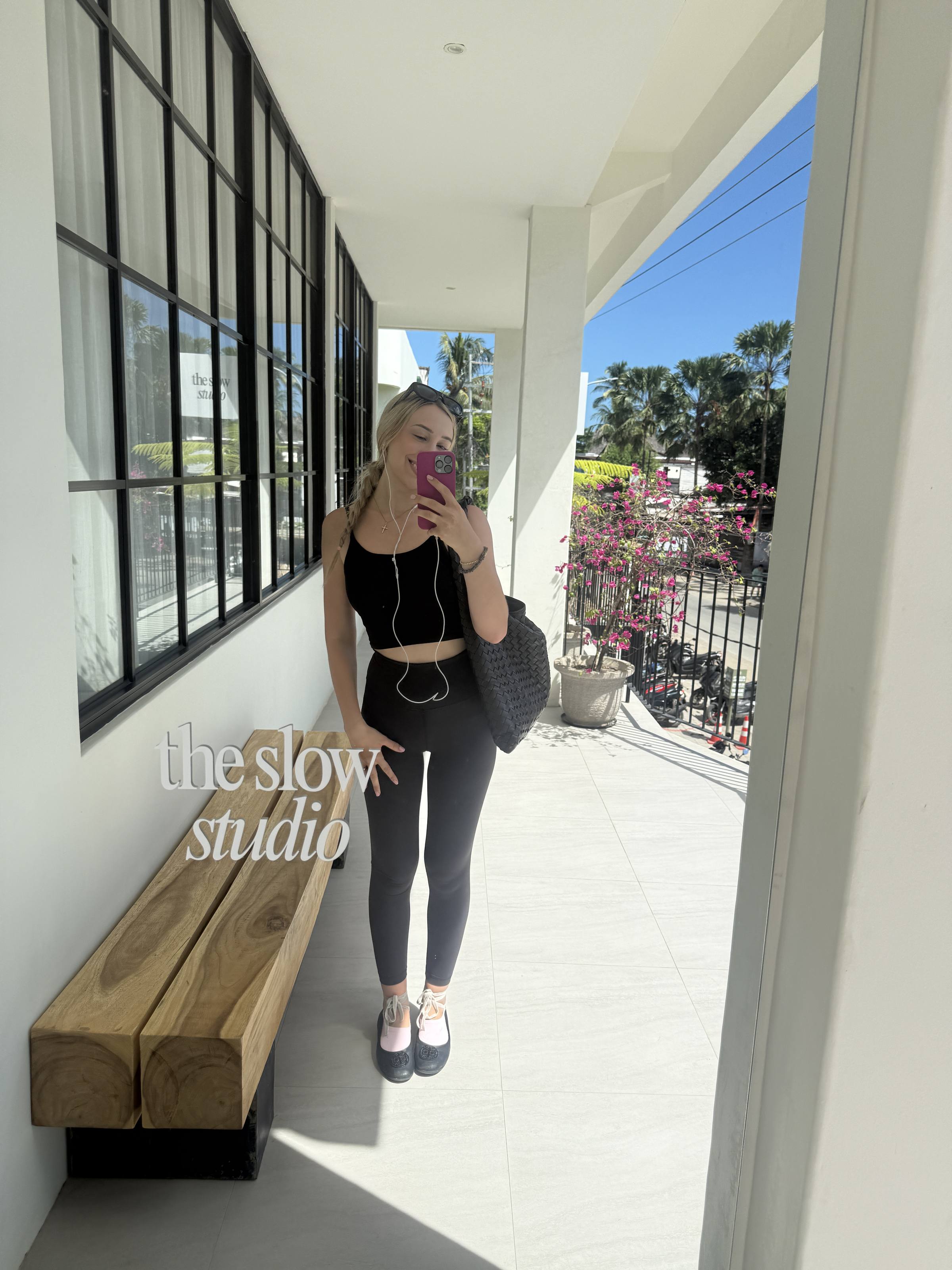 Standing in the doorway of a pilates studio, grip socks on, mirror selfie