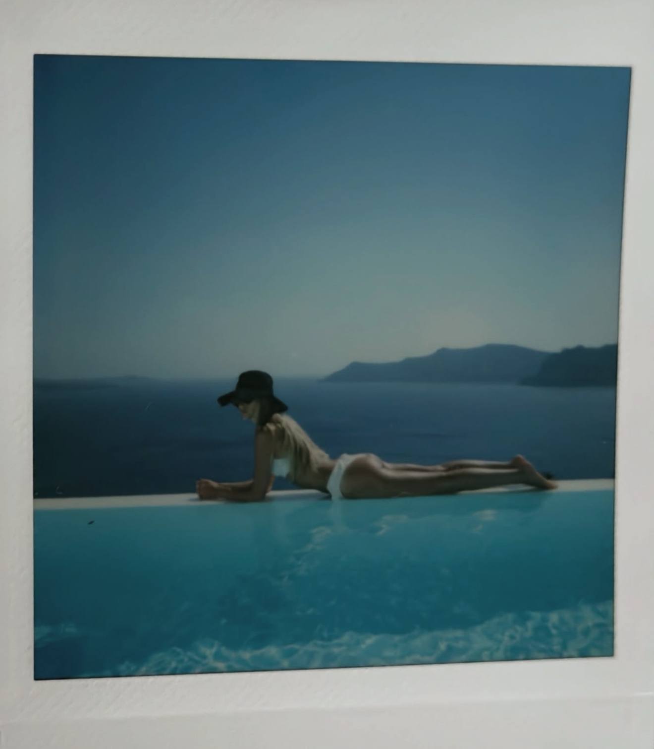 A framed print of a figure lying at the edge of an infinity pool