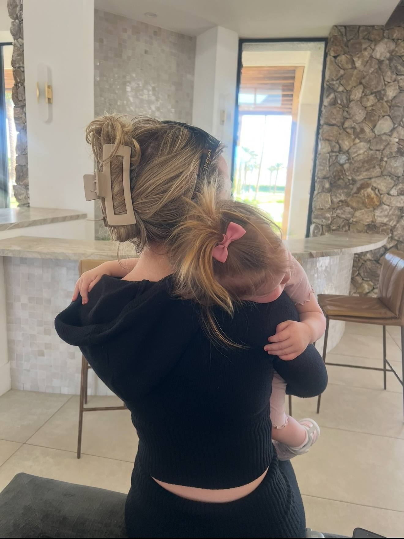 Holding a small child at the bar, hair up with a bow