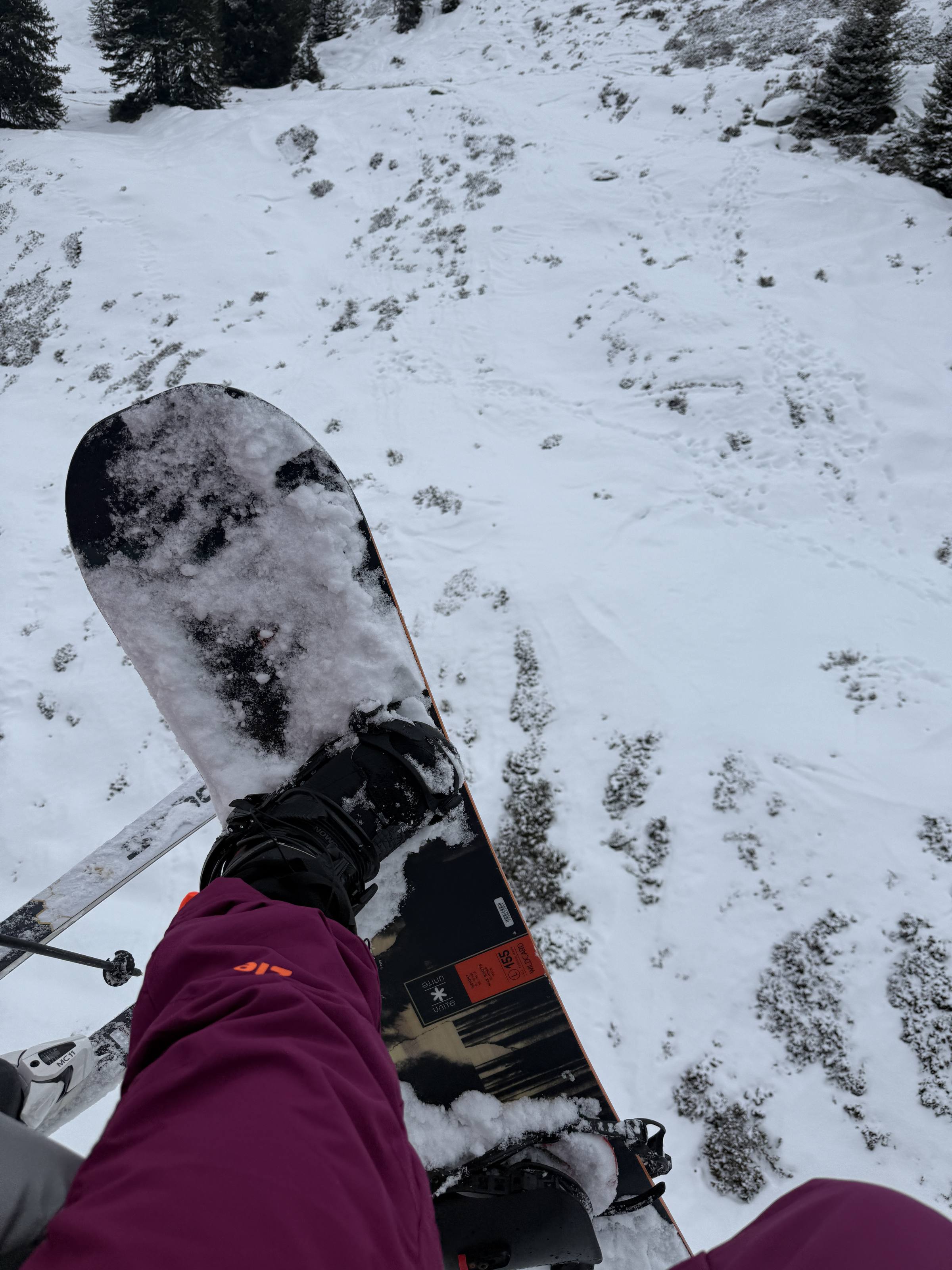 Looking down at a snowboard and boots from the chairlift, fresh snow below