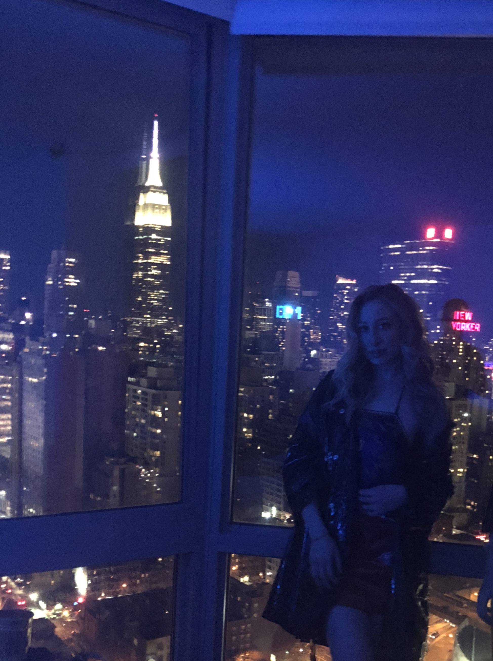 Midtown skyline at night through a corner window, the Empire State Building lit